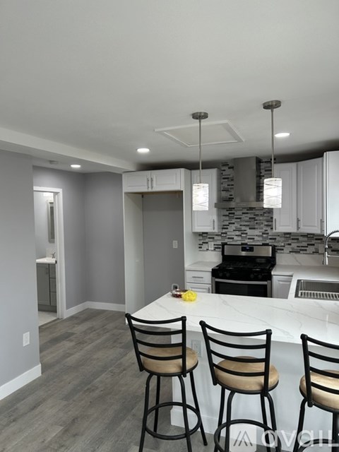 A kitchen with a white counter top and bar stools.