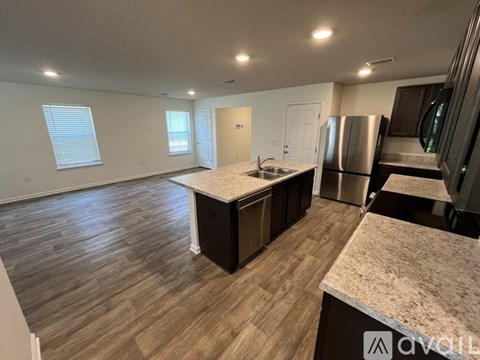 A kitchen with a stainless steel refrigerator and wooden flooring.