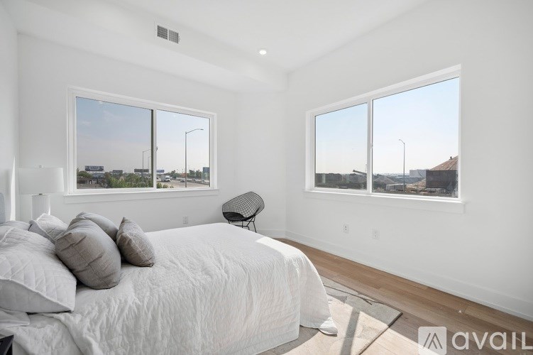 A bedroom with a large bed and a view of the city through the windows.