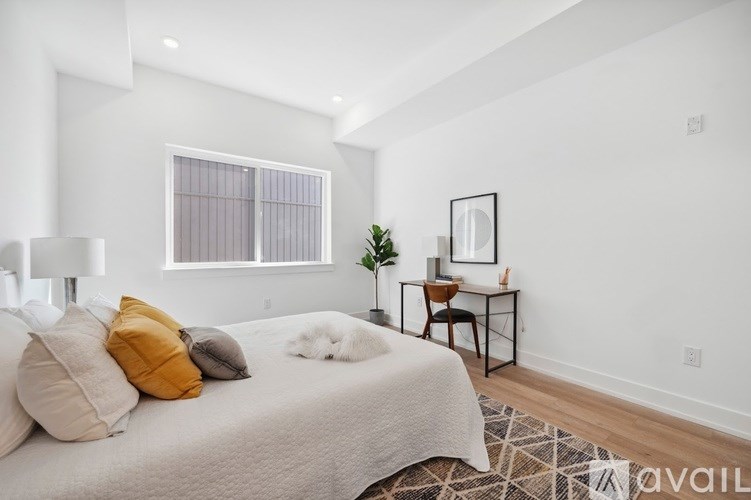 A bedroom with a bed, a desk, and a chair.