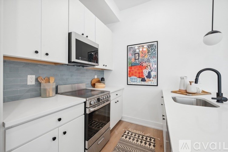 A kitchen with white cabinets and a grey backsplash.