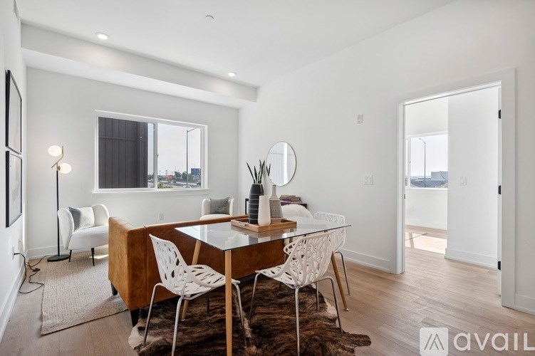 A modern dining room with a glass table and white chairs.