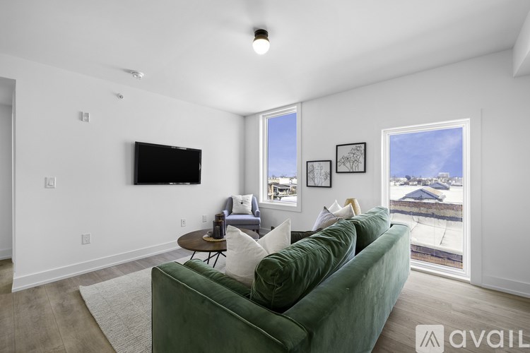 A living room with a green couch and a flat screen TV mounted on the wall.