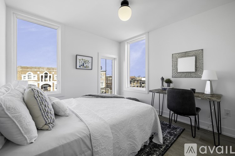 A bedroom with a large bed and a desk with a chair.