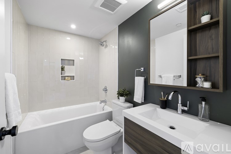 A modern bathroom with a white tub, sink, and toilet.