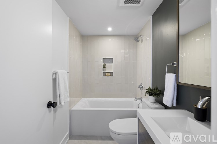 A modern bathroom with a white tub, toilet, and sink.