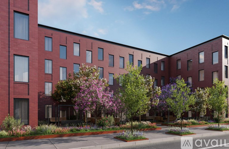 A red brick building with trees and bushes in front.