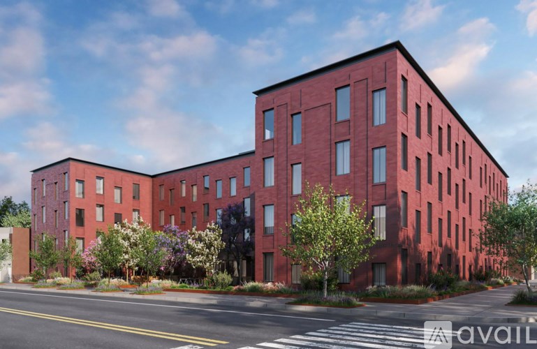 A red brick building with trees and bushes in front.