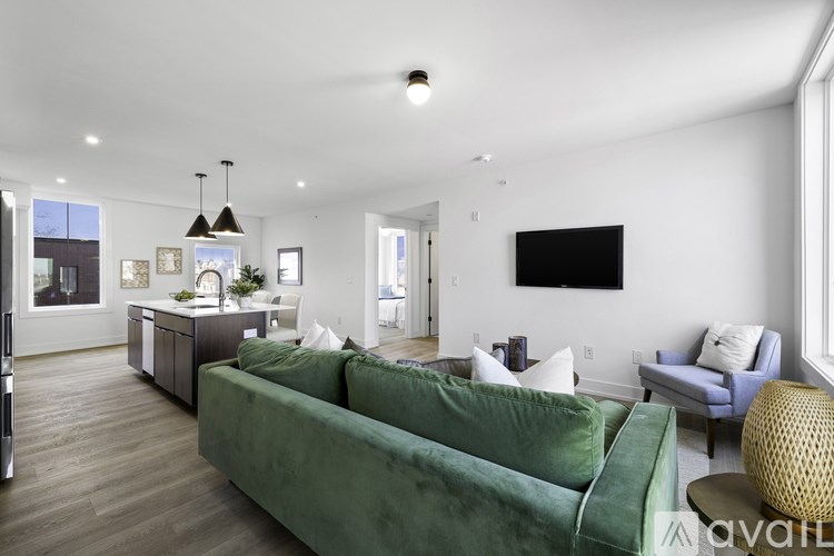 A living room with a green couch and a television on the wall.