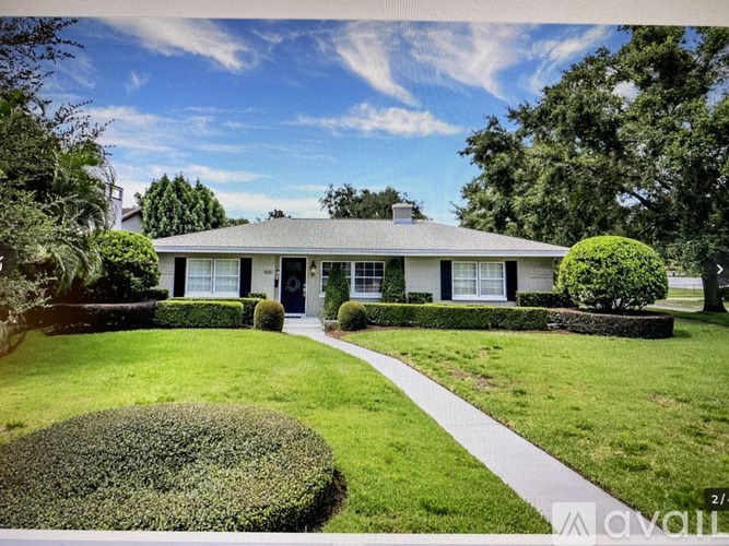 A white house with a black roof and a green lawn in front.