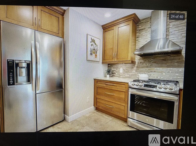 A kitchen with a stainless steel refrigerator, oven, and a picture on the wall.