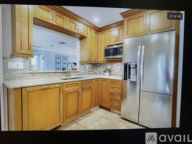 A kitchen with wooden cabinets and a stainless steel refrigerator.