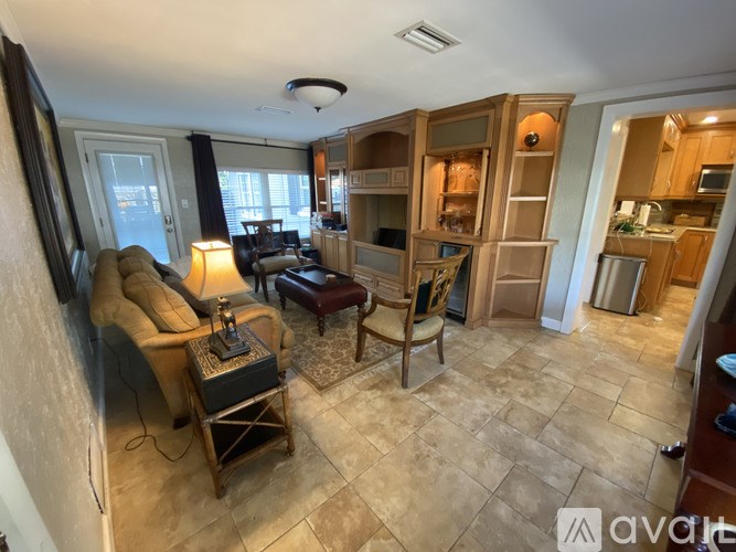 A living room with a couch, chair, and a table with a lamp on it.