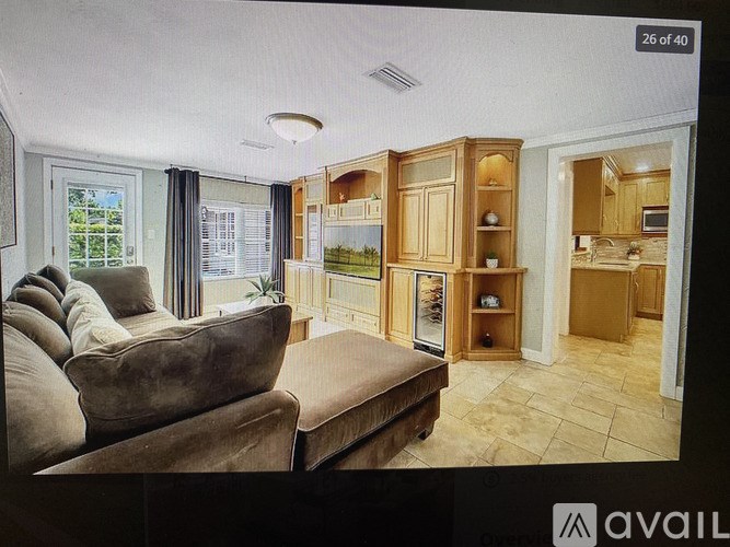 A living room with a brown couch and wooden cabinets.