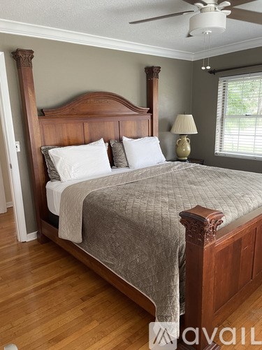 A bed with a wooden headboard and footboard with a grey comforter and pillows.