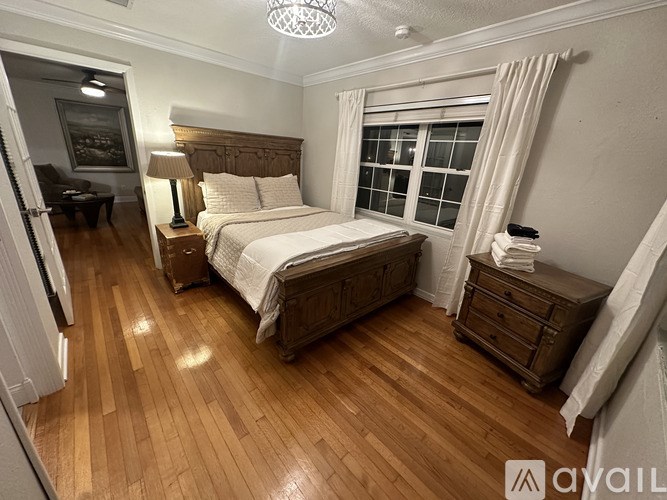 A bedroom with a large bed and wooden floors.
