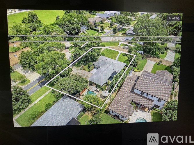 A large screen displays an aerial view of a residential area with a house in the foreground and a street running through the middle.