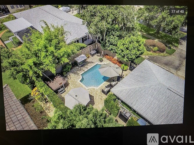 A house with a pool surrounded by trees and bushes.