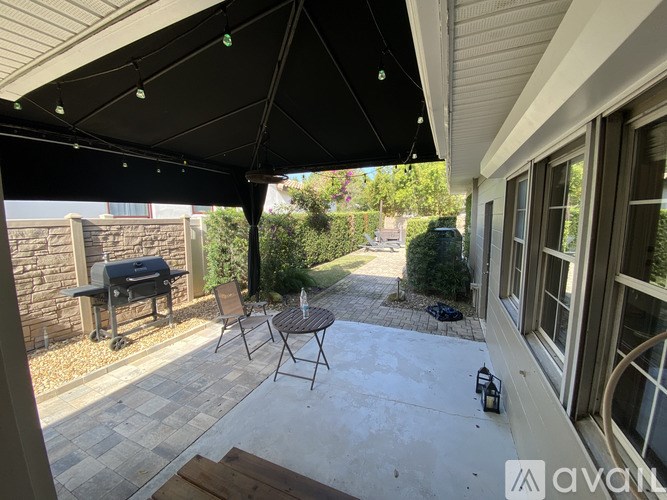 A patio with a table and chairs under a black awning.