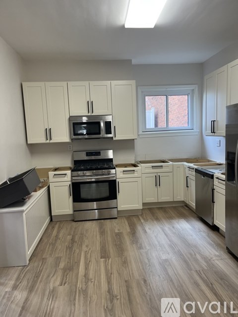 A kitchen with white cabinets and wood flooring.