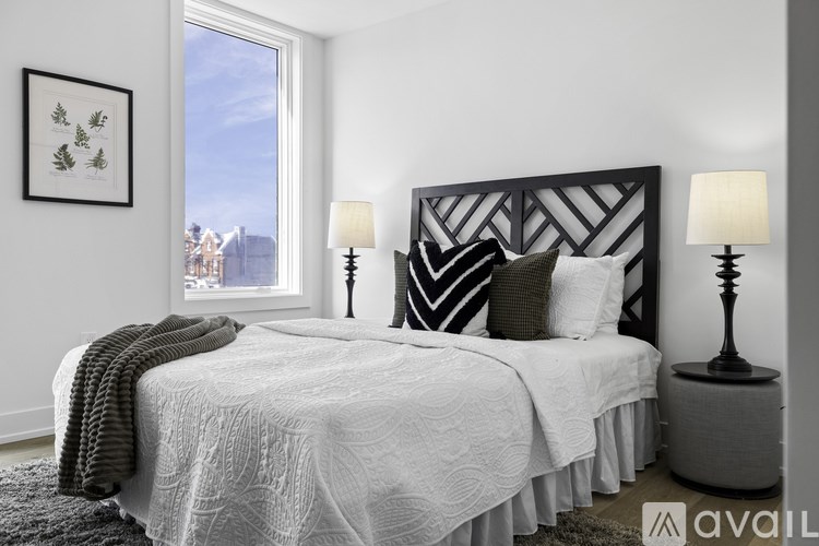 A bedroom with a large bed and a window overlooking a cityscape.