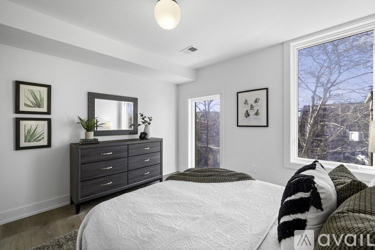 A bedroom with a large bed, a dresser, and a window overlooking a snowy landscape.