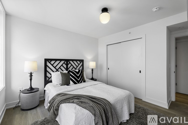 A bedroom with a bed, two lamps, and a large window.