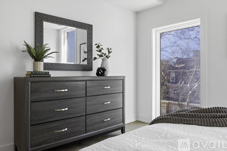 A bedroom with a large mirror, a dresser, and a window overlooking a snowy landscape.