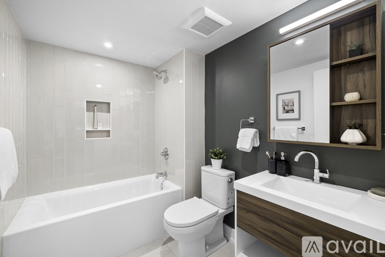 A modern bathroom with a white bathtub, toilet, and sink.