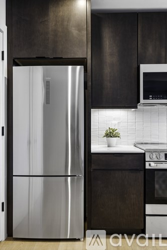 A modern kitchen with a stainless steel refrigerator and dark wood cabinets.