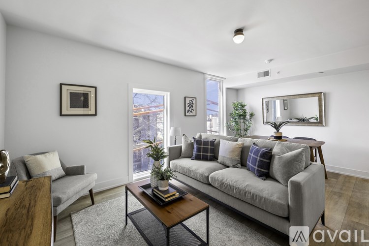 A living room with a grey couch, a coffee table, and a large window.