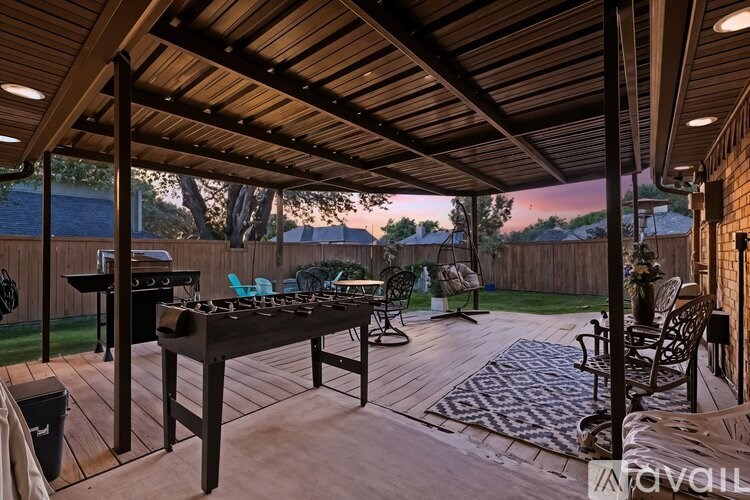 A wooden deck with a table and chairs under a roof.