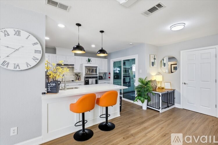 A kitchen with a bar area and a large clock on the wall.