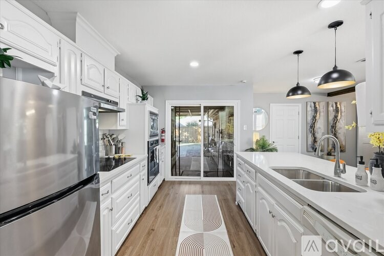 A modern kitchen with white cabinets and stainless steel appliances.