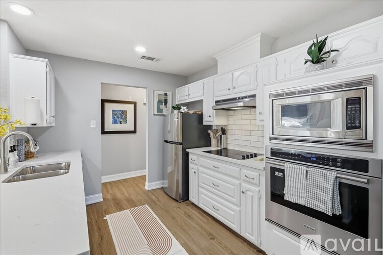 A modern kitchen with white cabinets and stainless steel appliances.