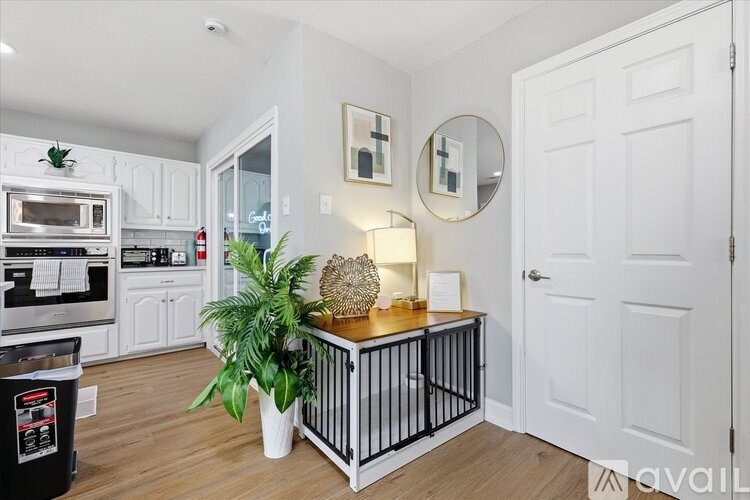 A kitchen with white cabinets and a black trash can.