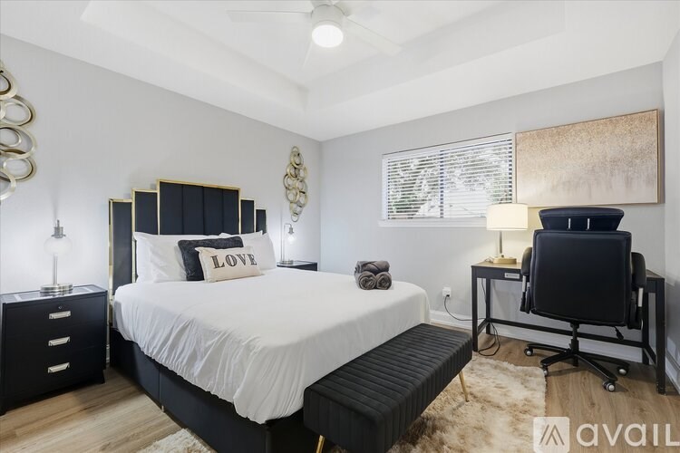 A bedroom with a large bed, a desk with a chair, and a painting on the wall.