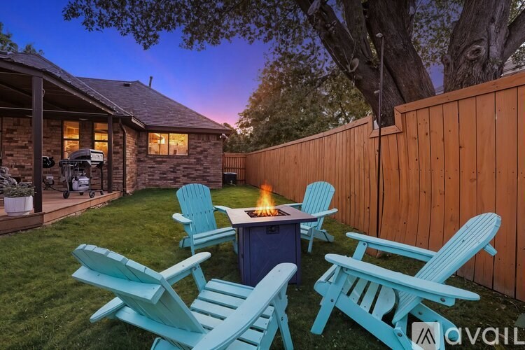 A backyard with a fire pit and chairs.