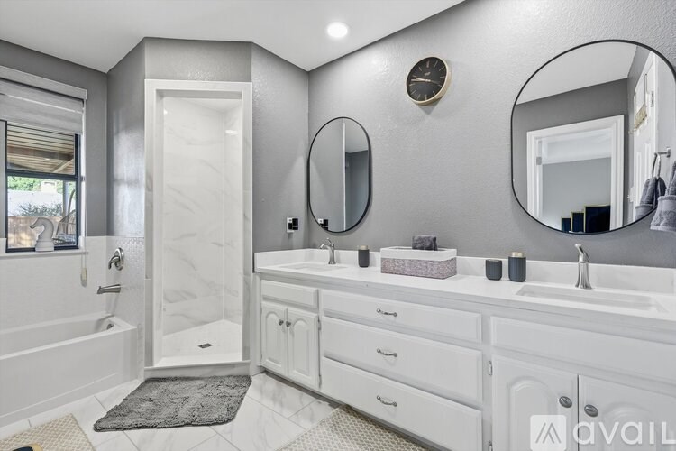 A bathroom with a white tub, sink, and mirror.