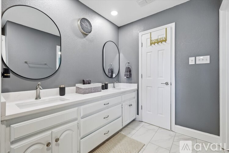 A bathroom with a white sink and a round mirror above it.