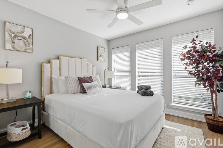 A bedroom with a large bed, a ceiling fan, and a potted plant.