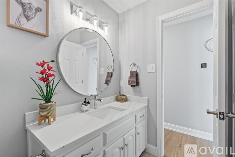 A bathroom with a white sink and a round mirror.