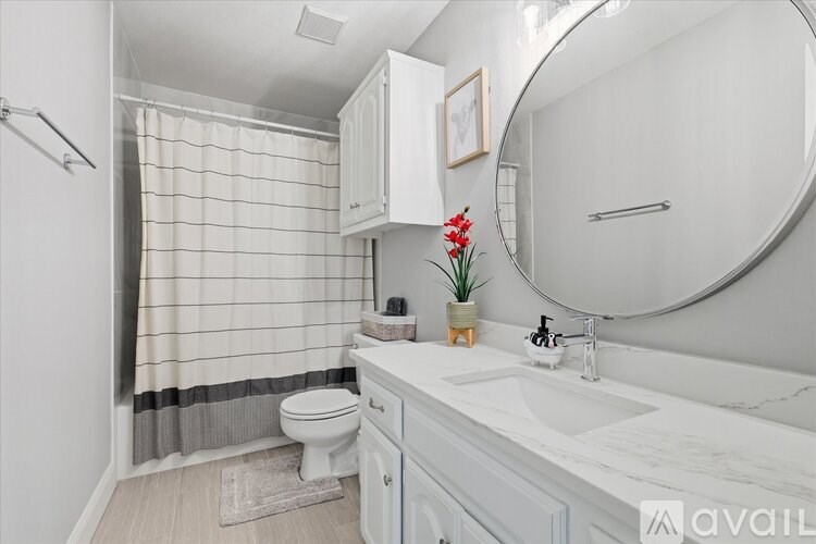 A bathroom with a white toilet, sink, and shower curtain.