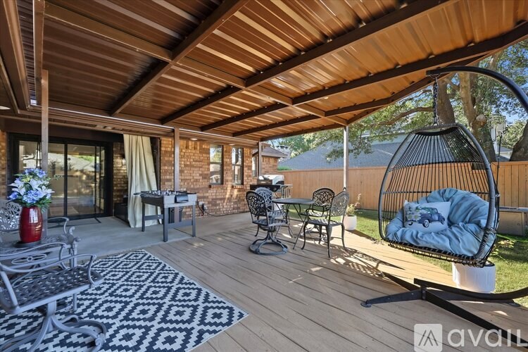 A wooden deck with a hanging chair and a table with chairs.
