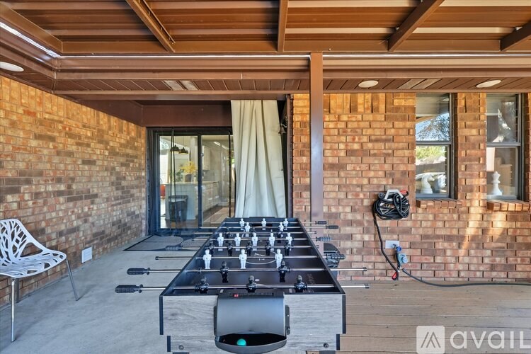 A foosball table is in the middle of a patio with a chair and a hose.
