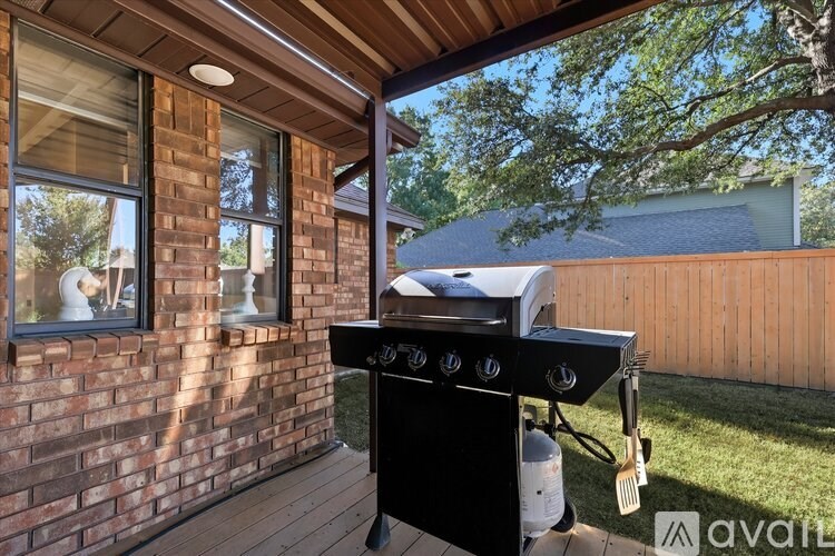 A black grill is on a wooden deck outside a house.