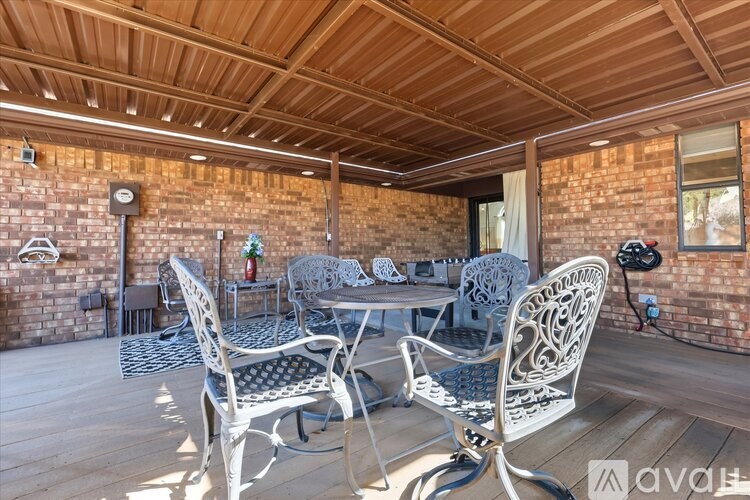 A patio with a table and chairs is set up on a wooden deck.