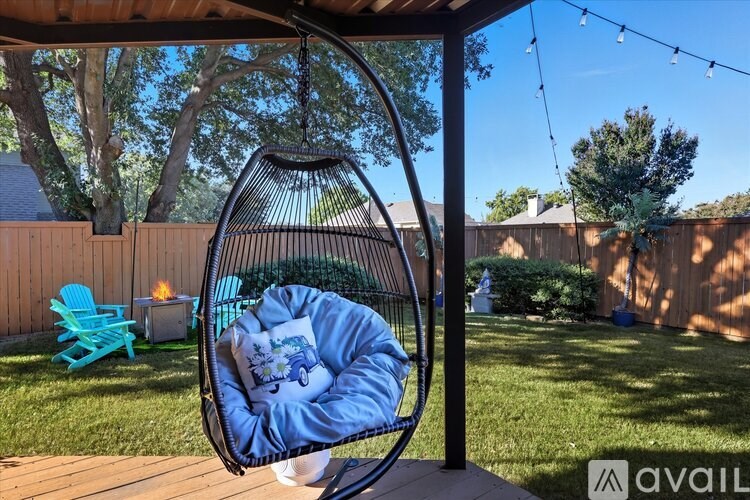 A person is sitting in a hanging egg chair on a deck.