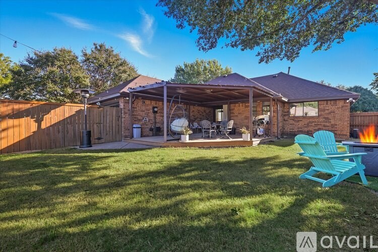 A backyard with a blue chair and a house in the background.