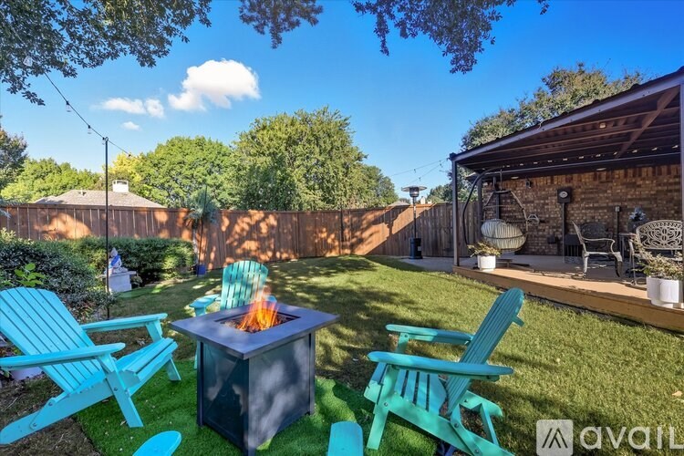 A backyard with a fire pit and chairs.